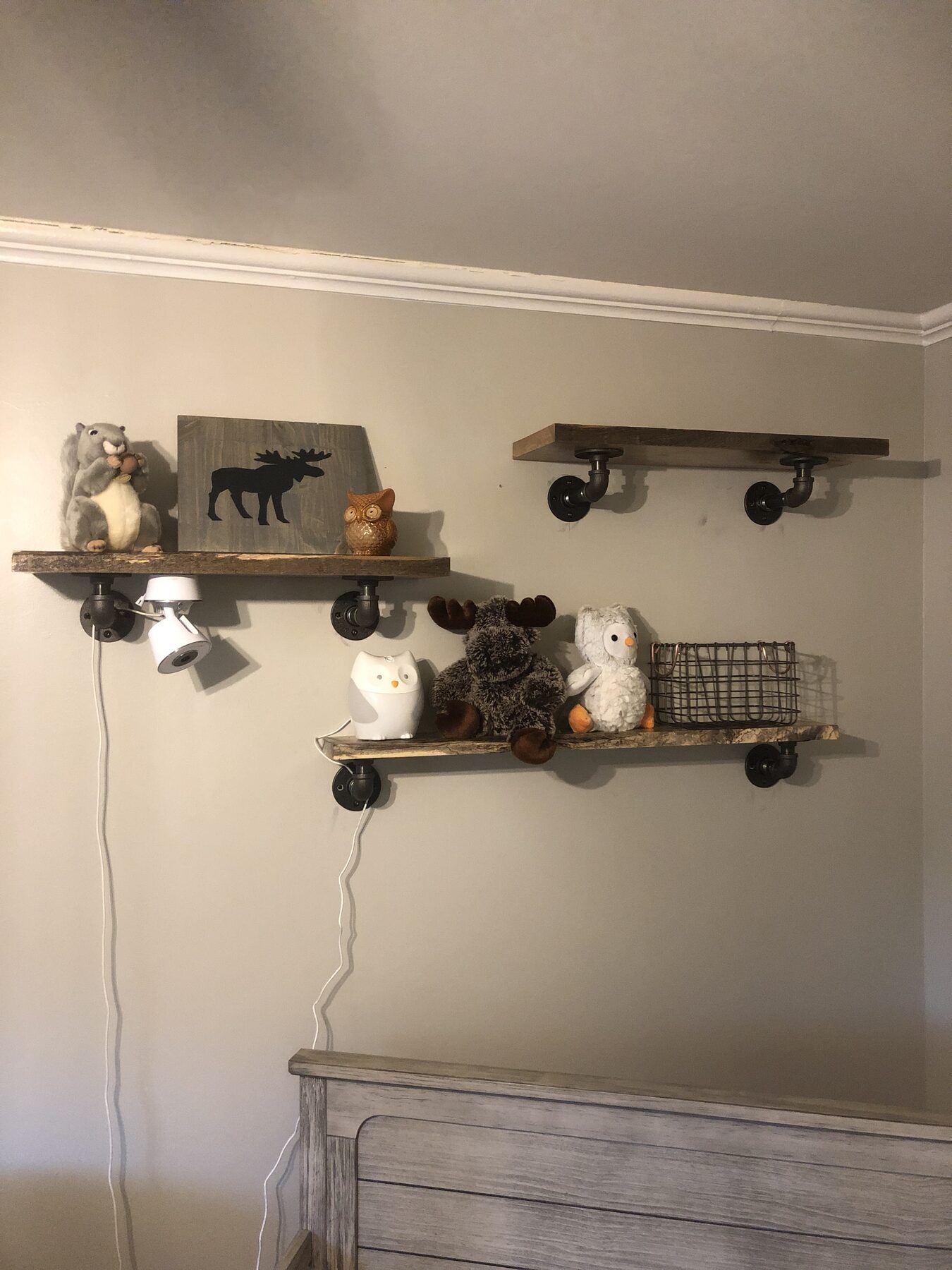 Two live-edge wood floating shelves mounted on black industrial pipe brackets and styled with decor