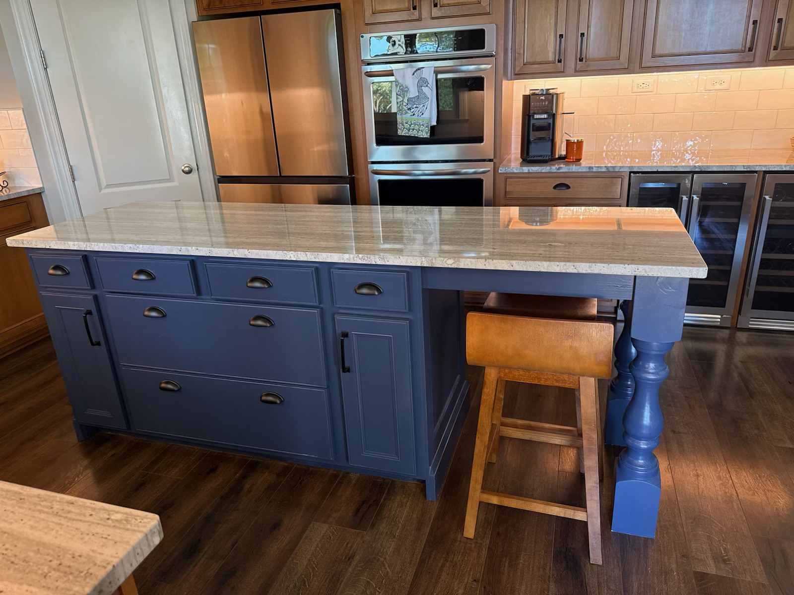 Reconditioned blue kitchen island with new center drawers, custom paneled sides, stone countertop and turned seating leg