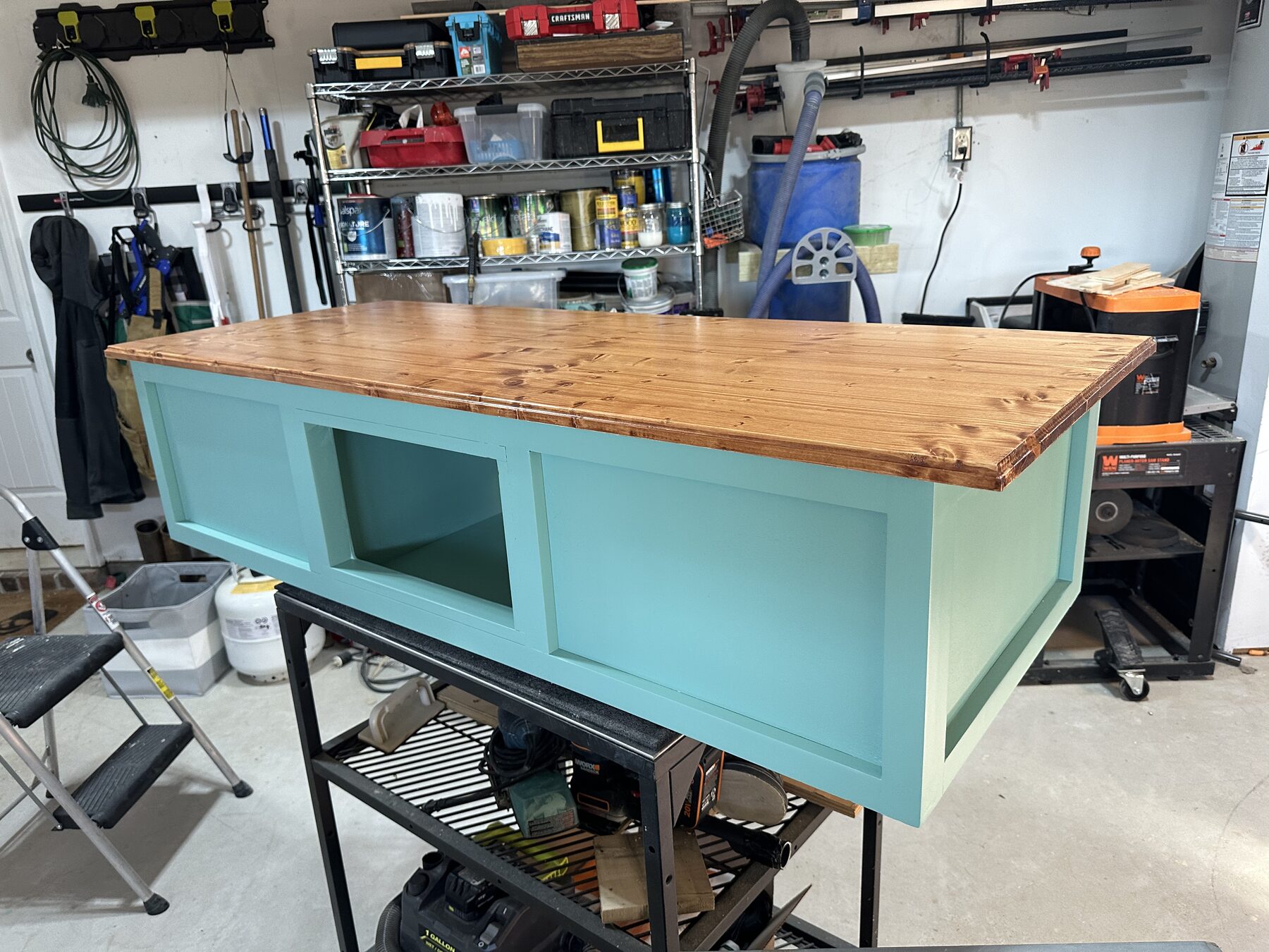 Shop-built seafoam painted coffee table with open shelving bays and a freshly finished butcher block top