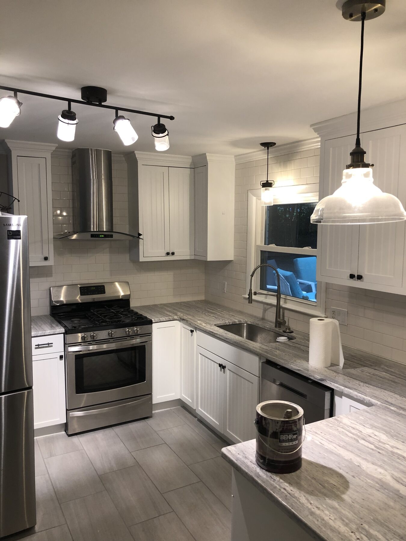 Completed white shaker kitchen with granite countertops, pendant lighting and stainless appliances